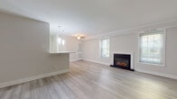This thoughtfully updated single-floor residence combines clean, modern finishes with a warm, inviting atmosphere throughout. The open-concept living and dining area is anchored by light-toned luxury vinyl plank flooring and a striking electric fireplace framed in black, serving as a natural focal point. Crown molding adds a refined architectural detail, while multiple windows dressed with blinds allow generous natural light to fill the space. A half-wall breakfast bar with pendant lighting seamlessly connects the living area to the kitchen, creating an open and functional layout. The kitchen is well-appointed with crisp white shaker cabinetry, quartz-style countertops, a full suite of black Whirlpool appliances including a range, over-the-range microwave, and dishwasher, plus a stainless steel sink. The bathroom showcases elegant marble-look tile on the floors, walls, and tub surround, complemented by a white vanity with quartz countertop and brushed nickel hardware. The bedroom features plush neutral carpeting and a generously sized double closet with sliding doors, offering substantial storage. The overall palette of soft whites and warm neutrals creates a cohesive, move-in-ready environment throughout.