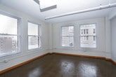 This single-floor unit blends industrial character with functional design, offering a layout that accommodates comfortable urban living. The open living area features polished concrete floors that reflect natural light streaming in through large windows, which frame notable views of surrounding city buildings. Exposed ductwork along the ceiling reinforces the loft-like, industrial aesthetic throughout the common areas. A pass-through counter connects the living space to the galley-style kitchen, which is equipped with light wood cabinetry, dark countertops, a double sink, and stainless steel appliances including a refrigerator, range, and dishwasher. Two windows in the kitchen allow additional natural light and continued city views.

The bedrooms feature warm, neutral carpet and ceiling fans with lighting. One bedroom benefits from a corner window configuration, while another includes a closet and direct access to the hallway. Two bathrooms serve the unit: one includes a walk-in glass shower, wood-toned vanity, and polished concrete flooring, while the second offers a full soaking tub with shower combination, a wide vanity with ample counter space, and a large mirror. Warm wood baseboards throughout provide a grounding contrast to the crisp white walls.