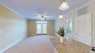 Located at 115 N Merrimon Ave in Woodfin, NC, this single-floor, 2-bedroom, 2-bathroom residence offers a thoughtfully designed layout with a comfortable sense of space throughout. The open-concept living and dining area is anchored by plush carpeting, crown molding, and a ceiling fan with light fixture. A chandelier adds an elegant touch, while French doors flood the space with natural light and provide access to the outdoors. The kitchen is well-equipped with warm-toned cabinetry, granite countertops, stainless steel appliances — including a refrigerator, range, microwave, and dishwasher — and a peninsula with pendant lighting that connects seamlessly to the living area. Tile flooring extends through the kitchen and bathrooms. Both bathrooms feature granite-topped vanities with rich wood cabinetry and tile flooring; one includes a tub-shower combination. The generously sized primary bedroom offers ample natural light and walk-in closet access, while the second bedroom also features a ceiling fan and bright windows. A dedicated laundry room with full-size washer and dryer and overhead cabinetry adds everyday convenience. With four closets total and a practical hallway connecting the spaces, this residence delivers functional, comfortable living in the Woodfin area.