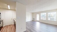 Located at 11704 Rustic View Ln in Fredericksburg, Virginia, this single-floor residence offers a thoughtfully arranged layout designed for comfortable everyday living. The open-concept living area is finished with light-toned, wood-style luxury vinyl plank flooring that extends throughout the main living and kitchen spaces, creating a cohesive and easy-to-maintain environment. Natural light flows generously into the living room through a combination of a glass exterior door and flanking windows, brightening the neutral white walls and textured ceiling. A floor-mounted HVAC vent provides efficient climate control throughout the space.

The kitchen is efficiently designed with gray cabinetry, light stone-look countertops, and stainless steel appliances including a dishwasher, offering a functional workspace that connects conveniently to the main living area via a pass-through or open partition.

The bedrooms are carpeted in a warm, neutral tone and receive natural light through standard windows, providing a comfortable and quiet retreat. The bathrooms are finished with clean, white fixtures, including a walk-in shower stall in one bathroom and a dedicated vanity area featuring dark wood cabinetry, a white countertop, and mirrored medicine cabinets, contributing to a practical and well-appointed design throughout.