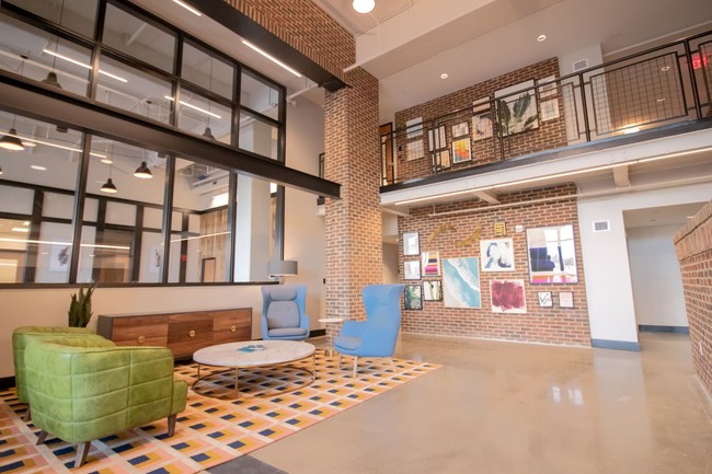 The main lobby at Penstock Quarter apartments in Henrico VA features a two story gallery wall and impressive brick details. - Penstock Quarter Apartments