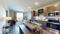 Located at 7600 Cabot Dr in Nashville, Tennessee, this thoughtfully designed one-bedroom, one-bathroom residence offers an efficient and stylish open-concept layout. Rich hardwood-style flooring flows throughout the main living areas, anchoring the seamless connection between the kitchen, dining, and living spaces. The modern kitchen is outfitted with dark espresso cabinetry, granite countertops, a classic white subway tile backsplash, and a full suite of stainless steel appliances, including a dishwasher, range, microwave, and refrigerator. A rustic wood dining table with bench seating sits adjacent to the kitchen, adding a warm, earthy contrast to the sleek finishes. The living room is bright and airy, highlighted by a large sliding glass door that opens onto a private balcony offering sweeping views of the surrounding hills and Nashville landscape. The bedroom features plush carpeting, a ceiling fan, generous natural light from multiple windows, and a dedicated closet. The bathroom includes dark cabinetry paired with granite countertops, a wide vanity mirror, and hardwood-style flooring. Neutral tones and recessed lighting throughout create a calm, inviting ambiance ideal for comfortable everyday living.