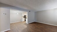 This single-floor unit presents a well-organized layout with a consistent neutral gray and beige color palette across all rooms. Textured ceilings are found throughout, complementing the clean white baseboards and trim work.

The living area features dark hardwood-style flooring and receives natural light through windows fitted with horizontal blinds. It connects openly to the galley-style kitchen, which is equipped with white cabinetry, light granite-style countertops, black appliances including a range and refrigerator, and a double sink. Track lighting illuminates the kitchen workspace, and the hardwood-style flooring continues seamlessly from the living area.

The bedrooms are carpeted in a warm beige tone and include ceiling fans with light fixtures, natural-light windows with blinds, and closet space. One bedroom features double bi-fold closet doors, providing ample storage.

The bathroom is efficiently designed with wood-style flooring, a white vanity with granite-style countertop, a full tub-shower combination, and clean white fixtures. A louvered closet door adjacent to the bathroom offers additional storage. Overall, the unit provides a practical and tidy living environment with cohesive finishes throughout.