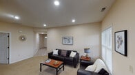 This single-floor residence offers a thoughtfully designed layout that balances comfort and functionality throughout. The entryway welcomes visitors with tile flooring and a front door featuring a fan-shaped transom window, setting a warm tone from the moment you arrive.

The main living area is anchored by a tile-surround fireplace with a wood mantel and built-in shelving, providing both a focal point and practical storage. Recessed lighting and neutral carpet flooring carry through the space, which opens seamlessly into a dedicated dining area bathed in natural light from multiple windows.

A secondary living or sitting room offers additional gathering space, featuring plush carpet, recessed lighting, and a window with outdoor views. The kitchen is well-equipped with warm wood cabinetry, granite-look countertops, a black appliance suite including a range and over-the-range microwave, and a sink with window access to natural light.

The residence includes multiple bedrooms, each finished with carpet flooring and windows that bring in ample daylight. One bedroom features a built-in desk area, ideal for work or study. Two full bathrooms serve the home; one includes a double-sink vanity with warm wood cabinetry, and the other offers a single-sink vanity with a shower-tub combination, both finished with tile flooring.