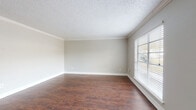 This single-floor residence offers a thoughtfully laid-out interior finished with rich, dark hardwood-style flooring that flows consistently throughout the space, creating a warm and cohesive aesthetic. The entryway welcomes visitors with a classic pendant light fixture, crisp white trim, and a large window that invites natural light from the outset.

The living area is generously proportioned, featuring elegant crown molding, neutral gray-toned walls, and a textured ceiling that adds depth to the room. A large window with blinds allows for excellent natural light and a view of the outdoors.

The galley-style kitchen is efficiently designed with dual runs of dark espresso cabinetry, granite-look countertops, a double-basin stainless steel sink, and black appliances including a refrigerator, dishwasher, and stovetop range — providing ample storage and prep space.

The bedrooms are comfortably sized, each equipped with a ceiling fan with light kit, neutral walls, and windows with blinds that offer natural light and privacy. The hardwood-style flooring continues seamlessly into these rooms.

Both bathrooms share a consistent design language, featuring dark vanity cabinetry with granite-look countertops, a single sink, full tub-shower combinations with tile surrounds, and matching hardwood-style flooring — offering a clean, functional finish throughout.