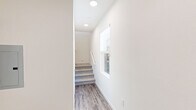 Located at 2601 Wagon Wheel Road in Oxnard, California, this generously sized three-bedroom, five-bathroom residence spans three floors, offering an impressive and versatile layout. The expansive ground floor serves as the foundation of the home and includes a dedicated underground parking structure with assigned spaces, providing secure and convenient access. Ascending to the main living level, an open-concept kitchen and living room combination creates a bright, welcoming gathering space. The kitchen is outfitted with sleek white cabinetry, light quartz countertops, stainless steel appliances, and wood-look flooring that extends throughout the living area. Large windows flood the living room with natural light, enhancing the clean, modern aesthetic. The upper floors house the three bedrooms, each featuring plush carpet flooring and generous closet space. The primary bedroom includes a well-appointed en-suite bathroom with a dual-sink vanity, ample cabinet storage, a walk-in shower, and wood-look tile flooring. The additional bathrooms are equally well-finished, with natural light provided by windows. A dedicated in-unit laundry area with a full-size washer and dryer adds everyday convenience. Throughout, the home maintains a consistent palette of neutral tones and contemporary finishes, creating a cohesive and refined living environment.