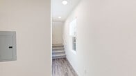 Located at 2601 Wagon Wheel Road in Oxnard, California, this generously sized three-bedroom, five-bathroom residence spans three floors, offering an impressive and versatile layout. The expansive ground floor serves as the foundation of the home and includes a dedicated underground parking structure with assigned spaces, providing secure and convenient access. Ascending to the main living level, an open-concept kitchen and living room combination creates a bright, welcoming gathering space. The kitchen is outfitted with sleek white cabinetry, light quartz countertops, stainless steel appliances, and wood-look flooring that extends throughout the living area. Large windows flood the living room with natural light, enhancing the clean, modern aesthetic. The upper floors house the three bedrooms, each featuring plush carpet flooring and generous closet space. The primary bedroom includes a well-appointed en-suite bathroom with a dual-sink vanity, ample cabinet storage, a walk-in shower, and wood-look tile flooring. The additional bathrooms are equally well-finished, with natural light provided by windows. A dedicated in-unit laundry area with a full-size washer and dryer adds everyday convenience. Throughout, the home maintains a consistent palette of neutral tones and contemporary finishes, creating a cohesive and refined living environment.