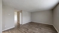 Located at 7816 Southside Blvd in Jacksonville, Florida, this two-floor residence offers a clean, modern aesthetic with thoughtfully designed living spaces throughout. The interior is finished with warm, neutral gray tones and a consistent design language that creates a cohesive and inviting atmosphere.

The main living area is generously sized and bathed in natural light through a bank of three windows fitted with white horizontal blinds. Dark wood-look plank flooring runs throughout the main living spaces, providing a stylish and durable foundation. Textured walls add subtle visual depth, while textured ceilings complement the overall design.

The kitchen is equipped with white cabinetry, dark laminate countertops, and stainless steel appliances including a refrigerator and dishwasher, all set on lighter wood-look flooring. A half bathroom nearby features matching flooring and clean white finishes.

The bedrooms are carpeted for added comfort, with one featuring a walk-in closet outfitted with wire shelving, and another with a spacious walk-through closet. The full bathroom includes a tub-shower combo, a white vanity with a dark countertop, a large mirror, and wood-look tile flooring. A dedicated walk-in closet with dual wire shelving systems provides exceptional storage capacity throughout the home.