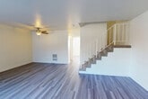 Located at 6401 Warner Ave in Huntington Beach, CA, this two-story, 3-bedroom, 2-bathroom home offers a well-organized layout spread across two floors. The main level features a bright, open living room with durable wood-style flooring, a ceiling fan with light fixture, and a staircase with white railings leading to the upper level. A wall-mounted heater provides climate control, while a hallway connects the living area to the rest of the main floor. The kitchen is well-appointed with white cabinetry, stainless steel appliances including a range, over-the-range microwave, and dishwasher, complemented by light wood-style flooring and ample overhead lighting. Upstairs, the spacious primary bedroom offers a ceiling fan, wood-style flooring, and natural light from a large window with vertical blinds. Additional bedrooms are carpeted and feature vertical blinds and sliding closet doors with built-in hanging rods. The bathrooms are finished in a clean, neutral palette with white vanities, light wood-style tile flooring, and a glass-enclosed walk-in shower. Hallways on both floors connect each space efficiently, completing this functional and well-maintained Huntington Beach home.