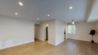 Located at 18551 Hatteras St in the Tarzana neighborhood of Los Angeles, this single-story residence offers a clean, modern aesthetic throughout. The open living area is finished with light-toned hardwood flooring, recessed lighting, and neutral walls, creating a bright and welcoming atmosphere. A ceiling fan adds functionality to the adjoining space, which benefits from natural light through blinded windows with greenery visible outside.

The kitchen is well-appointed with white shaker-style cabinetry, grey countertops, and a full suite of stainless steel appliances including a gas range, refrigerator, microwave, and dishwasher. A window above the sink allows natural light to fill the space.

The bedrooms feature plush wall-to-wall carpeting and recessed lighting. One bedroom includes a sliding mirrored closet with built-in shelving, while windows provide outdoor views and natural light in each room.

The bathroom is finished with a white vanity, grey countertop, square undermount sink, and framed mirrors, maintaining the home's consistent modern style. Light wood-look flooring completes the updated look. Overall, the space presents a cohesive, freshly updated interior with practical finishes throughout.