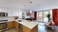 This contemporary 1070 square foot apartment in Campbell, CA offers a harmonious blend of style and functionality. The open-concept living area is the heart of the home, featuring a comfortable gray sectional sofa, vibrant red curtains, and large windows that flood the space with natural light. The adjacent kitchen boasts a sleek design with two-tone cabinetry, stainless steel appliances, and ample counter space, perfect for culinary enthusiasts.

The primary bedroom, measuring 210 square feet, is a serene retreat with a large window offering garden views. It's adorned with eye-catching red artwork and plush bedding in soothing gray tones. The second bedroom continues the modern aesthetic with a dark wood headboard and patterned curtains.

Both bathrooms exhibit a clean, minimalist design with large mirrors, floating vanities, and neutral color palettes. One bathroom features a spacious walk-in shower, while the other offers a full-size bathtub for relaxation.

The apartment also includes two hallways and two closets, providing ample storage space. The overall design aesthetic is cohesive, with a recurring theme of white walls accented by pops of red in artwork and decor, creating a vibrant yet sophisticated ambiance throughout the space.