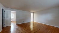 Located in Trenton, NJ, this single-floor unit offers a well-organized layout comprising a living room, kitchen, bathroom, and two closets. The living room is a standout space, featuring warm, polished hardwood floors that extend throughout the unit, neutral light gray walls, and clean white baseboards that give the room a bright, airy feel. A window provides natural light and a view of surrounding greenery, while a wall-mounted radiator ensures comfortable heating. The entryway area continues the hardwood flooring theme, with a solid white entry door accented by brass hardware.

The kitchen is efficiently designed with white cabinetry, a stainless steel gas range, a full-size stainless steel refrigerator, and light granite countertops. Light tile flooring, a window overlooking the outdoors, and a radiator unit complete the functional space. The bathroom is well-appointed with a white vanity featuring a granite countertop, an overhead cabinet, a framed mirror, tile flooring, and a window with blinds that allows natural light in. Two closets provide practical storage, each featuring a full-width hanging rod and hardwood flooring. Overall, the space presents a clean, functional, and comfortable living environment.
