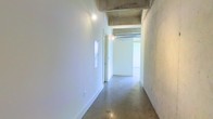 This single-floor space showcases a striking industrial-modern design that seamlessly blends raw architectural elements with clean, minimalist finishes. The exposed concrete ceiling beams and columns give the space a bold, structural character, while the polished concrete floors add a sleek, cohesive foundation that reflects light and enhances the sense of openness throughout.

The crisp white walls contrast beautifully against the raw concrete surfaces, creating a bright and airy atmosphere that feels both expansive and versatile. Recessed and track lighting are integrated into the ceiling, providing warm, focused illumination that complements the natural brightness of the space.

A wide corridor connects the areas of the floor, offering a clear and open flow between spaces. The layout is open and unobstructed, lending itself well to a variety of uses, from creative studios and galleries to commercial or office environments. The combination of industrial materials and minimalist design creates an ambiance that is both functional and visually compelling — a blank canvas ready to be tailored to its occupant's vision.