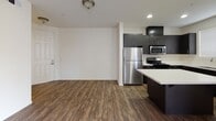 Located at 1056 E Philadelphia St in Ontario, CA, this single-story unit offers a well-designed, open-concept layout that seamlessly connects the kitchen, dining, and living areas. Rich dark wood-style flooring flows throughout the main living spaces, creating a warm and modern aesthetic.

The kitchen is a standout feature, equipped with dark espresso cabinetry, white countertops, a center island, and a full suite of stainless steel appliances including a gas range, over-the-range microwave, dishwasher, and refrigerator. A deep stainless steel sink and ample upper and lower cabinet storage add to its functionality. Recessed lighting brightens the kitchen area effectively.

The open living room is generously sized, bathed in natural light from multiple windows, and accesses a private balcony through a sliding glass door. A ceiling fan enhances comfort throughout the main living area.

The bedroom features plush carpeting, a ceiling fan, a large window for natural light, and a walk-in closet with built-in shelving. The bathroom is clean and modern, outfitted with dark vanity cabinetry, white countertops, a tub-shower combination with sliding glass doors, and a large mirror with overhead lighting. An in-unit laundry area is also present, adding everyday convenience.