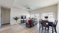 This single-story residence offers a thoughtfully designed open-concept layout with a clean, modern aesthetic. Light wood-style flooring flows consistently throughout, tying the spaces together cohesively.

The living area is anchored by vaulted ceilings and a ceiling fan, creating an airy, open atmosphere. Large windows invite natural light and provide outdoor views, while the adjoining dining area ensures a seamless connection between living and entertaining spaces.

The kitchen is a standout feature, showcasing white shaker cabinetry extending to the ceiling, light quartz countertops, a grey tile backsplash, and a full suite of stainless steel appliances including a French door refrigerator and electric range. A kitchen island with a deep sink adds prep space, and a walk-in pantry provides generous storage. A tray ceiling with a sputnik chandelier adds architectural interest overhead.

The bedrooms offer comfortable retreats, each with natural light from windows with blinds and wood-style flooring. The primary suite includes a spacious walk-in closet with built-in shelving and a private bathroom featuring a tiled walk-in shower and a white vanity with tile flooring. A dedicated laundry area houses a stacked full-size washer and dryer.