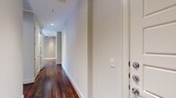 This single-floor residence offers a well-appointed layout with a consistent design language throughout. Entry is made through a solid, multi-lock door that opens into a long corridor finished with rich, dark hardwood flooring and recessed lighting, setting an elegant tone from the start.

The open-concept living and dining area is defined by its generous proportions, warm hardwood floors, crown molding, and large windows that frame urban views while flooding the space with natural light. Track lighting provides additional illumination across the living zone.

The kitchen features dark espresso cabinetry, stainless steel appliances including a French door refrigerator, electric range, and microwave, complemented by granite countertops with a decorative tile backsplash. Pendant lights hang above a granite-topped peninsula that provides additional counter space and a built-in seating ledge, seamlessly connecting the kitchen to the living area.

The bedrooms are carpeted for comfort and include generous closet space with built-in shelving and ceiling fans. One bedroom benefits from large windows with urban views and access to an adjacent space. The bathroom is finished with tile flooring, a granite vanity with dark cabinetry, and a glass-enclosed tile shower.