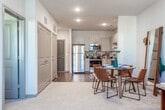 This single-floor residence at 1877 Riverside Pkwy in Douglasville, GA offers a well-designed layout with modern finishes throughout. The kitchen is a standout feature, outfitted with light wood-grain cabinetry extending to the ceiling, granite countertops, a tiled backsplash, and a full suite of stainless steel appliances including a refrigerator, electric range, built-in microwave, and dishwasher. Rich hardwood-style flooring grounds the kitchen and transitions into the open dining area, creating a seamless connection between cooking and entertaining spaces. The living room is carpeted and features a ceiling fan, multiple windows that invite natural light, and generous wall space suited for artwork. An open sightline connects the living and dining areas to the kitchen, enhancing the sense of space. The bedroom is appointed with plush carpet, a ceiling fan, and a bold teal accent wall that adds a vivid focal point to the room. Natural light filters in through windows dressed with curtain panels. The bathroom features hardwood-style flooring, a vanity with a single sink, and a shower-tub combination, all presented in a clean, neutral palette that complements the home's contemporary aesthetic.