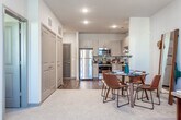 This single-floor residence at 1877 Riverside Pkwy in Douglasville, GA offers a well-designed layout with modern finishes throughout. The kitchen is a standout feature, outfitted with light wood-grain cabinetry extending to the ceiling, granite countertops, a tiled backsplash, and a full suite of stainless steel appliances including a refrigerator, electric range, built-in microwave, and dishwasher. Rich hardwood-style flooring grounds the kitchen and transitions into the open dining area, creating a seamless connection between cooking and entertaining spaces. The living room is carpeted and features a ceiling fan, multiple windows that invite natural light, and generous wall space suited for artwork. An open sightline connects the living and dining areas to the kitchen, enhancing the sense of space. The bedroom is appointed with plush carpet, a ceiling fan, and a bold teal accent wall that adds a vivid focal point to the room. Natural light filters in through windows dressed with curtain panels. The bathroom features hardwood-style flooring, a vanity with a single sink, and a shower-tub combination, all presented in a clean, neutral palette that complements the home's contemporary aesthetic.