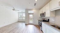Located at 2705 Haverford Pl in Charlotte, NC, this efficiently designed single-floor unit offers a bright and modern living experience. The open-concept layout seamlessly connects the living area and kitchen, both finished with light-toned luxury vinyl plank flooring that extends throughout the space.

The kitchen is a standout feature, outfitted with crisp white shaker cabinetry, granite countertops, a subway tile backsplash, and a full suite of stainless steel appliances including an electric range, microwave, dishwasher, and refrigerator. A single-basin sink with a brushed nickel faucet completes the functional workspace. A sliding barn door adds a contemporary architectural detail near the kitchen area.

The living area is bathed in natural light through large windows and a glass-paneled entry door with a transom window above. A ceiling fan overhead ensures year-round comfort. The entrance provides a welcoming transition into the open living space.

The bathroom features a soaking tub with full subway tile surround and brushed bronze fixtures, offering a clean and polished finish. Throughout the unit, bright white walls and recessed lighting contribute to an airy, modern ambiance, making this a well-appointed and efficiently organized space in the heart of Charlotte.