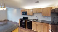 This single-floor residence offers a well-organized layout that balances practicality and comfort throughout its distinct spaces. The kitchen is a standout area, outfitted with light maple cabinetry extending to the ceiling for ample storage, dark granite countertops, and a full suite of black appliances including a range, over-the-range microwave, dishwasher, and refrigerator. A classic white subway tile backsplash adds a clean, timeless detail, while wood-style flooring runs continuously underfoot, connecting the kitchen to the main living areas.

The bedroom is a bright, comfortable space featuring the same warm wood-style flooring, neutral walls, and a ceiling fan with integrated lighting. Two windows fitted with horizontal blinds allow for natural light and ventilation. A walk-in closet adjacent to the bedroom provides generous storage with wire shelving and hanging rods along multiple walls.

The bathroom is designed for efficiency, featuring large-format gray tile flooring, a light maple vanity with a white countertop, a wide mirror, and chrome hardware accents. Towel bars and a curtained shower area complete the functional layout. Throughout the unit, neutral tones and consistent finishes create a cohesive, move-in-ready atmosphere.