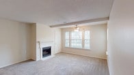 This single-floor, three-bedroom, two-bathroom residence at Magnolia East offers a well-designed layout that balances comfort and functionality. The spacious living room is a standout feature, highlighted by a tiled fireplace with a classic white mantle, a ceiling fan, and a large multi-pane window that fills the room with natural light. Soft carpeting throughout the living areas adds warmth and comfort underfoot. Adjacent to the living room, the dining area transitions seamlessly to the kitchen via wood-style flooring, creating a cohesive open feel. The kitchen is outfitted with white cabinetry, dark countertops, and white appliances including a range, over-the-range microwave, and dishwasher. Each of the three bedrooms features plush carpeting, standard closets with wire shelving, and windows that bring in natural light. The two bathrooms are finished with white cabinetry, dark countertops, large vanity mirrors, and tub-shower combinations. A dedicated laundry area houses a full-size washer and dryer with overhead shelving for added storage. The neutral color palette and textured ceilings throughout lend the home a clean, move-in-ready appeal.
