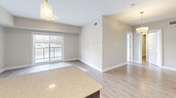 Located at 1355 Commissioners Rd W in London, Ontario, this well-appointed 2-bedroom, 2-bathroom unit offers a thoughtfully designed layout with modern finishes throughout. Light-toned laminate flooring runs throughout the space, complemented by neutral warm-beige walls and crisp white trim, creating a clean and cohesive aesthetic.

The open-concept living, dining, and kitchen area serves as the heart of the unit. The kitchen is outfitted with stainless steel appliances including a full-size refrigerator, electric range, and over-the-range microwave, paired with two-tone cabinetry featuring dark wood lower cabinets and white upper cabinets, a subway tile backsplash, and a light quartz countertop with a peninsula. Pendant lighting adds a stylish touch. Sliding glass doors in the living area open to a private balcony, allowing natural light to fill the space.

Both bedrooms are generously sized with large windows that invite natural light and outdoor views. The primary bedroom features a dedicated walk-in closet with wire shelving, while the second bedroom includes a double closet. The ensuite bathroom offers a frameless glass walk-in shower with tile surround and a floating vanity, while the second bathroom features a tiled tub-shower combo and matching vanity. An in-unit laundry area completes this well-rounded residence.