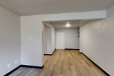 Located at 6 Flats #3 in Sioux Falls, South Dakota, this two-bedroom, one-bathroom unit offers a practical and well-organized single-floor layout. The space features a mix of light gray luxury vinyl plank flooring in the main living areas and kitchen, with plush carpeting in the bedrooms for added comfort.

The galley-style kitchen is equipped with white cabinetry, light granite-style countertops, a double-basin sink, and white appliances including a range and refrigerator. Ample upper and lower cabinet storage makes the kitchen both functional and efficient.

Each bedroom benefits from wide, horizontal windows that allow natural light to fill the rooms while offering views of the surrounding neighborhood. Baseboard heating runs along the walls, ensuring year-round comfort. The primary bedroom is generously proportioned and includes a closet with built-in shelving, while the secondary bedroom also features a closet and carpeted flooring.

The bathroom is finished with white subway tile wainscoting, a tub-shower combination, and wood-look flooring, creating a clean and classic look. Neutral gray walls throughout the unit provide a versatile backdrop. The textured ceilings and bold black baseboards add subtle architectural character to the overall design.