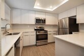 Located at 2508 Associated Rd in Fullerton, California, this single-floor residence offers a clean, modern aesthetic with a thoughtfully designed open-concept layout. The spacious living area is finished with warm wood-style flooring and soft gray walls, creating a bright and welcoming atmosphere. A ceiling fan with integrated lighting anchors the main living space, which flows seamlessly toward the kitchen via a peninsula counter — ideal for both casual dining and entertaining.

The kitchen is well-appointed with crisp white flat-front cabinetry, white quartz countertops, and a full suite of stainless steel appliances including a gas range, built-in microwave, refrigerator, and dishwasher. A skylight above the kitchen adds an abundance of natural light, while a window over the sink frames views of the surrounding greenery.

An elegant arched doorway connects the main living area to the hallway, adding a subtle architectural charm. The bathroom features a full tub-shower combination with chrome fixtures and wood-style flooring. The bedrooms are carpeted for comfort and include windows with blinds that bring in natural light and outdoor views of palm trees and lush landscaping, reinforcing the Southern California setting throughout.