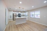 Located at 4386 Jackson St in Punta Gorda, FL, this single-floor home has been thoughtfully updated with modern finishes throughout. Light-toned luxury vinyl plank flooring runs continuously across the living areas and bedrooms, creating a bright, cohesive aesthetic that complements the neutral gray walls and crisp white trim.

The kitchen is a standout feature, outfitted with white shaker-style cabinetry accented by gold hardware, a subway tile backsplash, quartz countertops, and a full suite of stainless steel appliances including a refrigerator, electric range, and over-the-range microwave. A kitchen island with pendant lighting adds both function and style, while multiple windows invite natural light and outdoor views.

The bedrooms are generously proportioned, each equipped with ceiling fans featuring gold-toned fixtures and recessed lighting. At least one bedroom includes a built-in closet with sliding doors, offering practical storage. The living and entry areas are open and airy, with natural light filtering through large windows.

The bathroom showcases a walk-in glass shower with large-format stone-look tile on the walls and a mosaic tile floor, complemented by a built-in bench — a clean and refined finish. Throughout the home, recessed lighting, fresh paint, and consistent flooring tie together a move-in ready interior designed for comfortable Florida living.