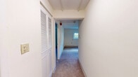 This single-floor, one-bedroom, one-bathroom unit in Seabrook, NH, offers a functional and well-organized layout across its five rooms. The living room features neutral-toned carpet flooring, baseboard heating, and a wide window that welcomes natural light and outdoor greenery views, along with a wall-mounted air conditioning unit for year-round comfort. The kitchen is equipped with warm wood-toned cabinetry, laminate countertops, and hardwood-style flooring, along with included appliances such as a refrigerator, dishwasher, stovetop, and microwave. A dedicated entry door leads directly from the kitchen, adding convenience. The bedroom is a comfortably sized room with plush carpet flooring, a large sliding-door closet for ample storage, and a window that provides natural light and views of the surrounding area. Baseboard heating is present throughout. The bathroom features a clean, white full tub/shower combo with a built-in corner shelf, mosaic tile flooring, and classic fixtures. Neutral cream-toned walls and consistent finishes throughout the unit create a cohesive, understated aesthetic. A connecting hallway ties all rooms together for a smooth flow across the home.