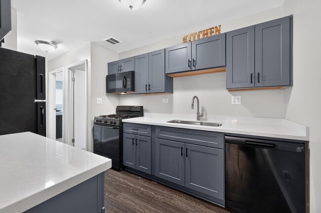 Prepara algo delicioso en esta elegante cocina con electrodomésticos y gabinetes negros en Renaissance at Carol Stream en Carol Stream, Illinois. - Renaissance at Carol Stream