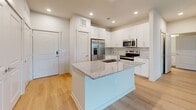 Located at 11305 Grant Rd in Houston, TX, this single-story, one-bedroom, one-bathroom unit offers a thoughtfully designed layout with modern finishes throughout. Light-toned hardwood flooring flows seamlessly across the entire space, creating a cohesive and clean aesthetic.

The open-concept kitchen serves as a centerpiece, featuring crisp white shaker cabinetry extending to the ceiling, granite countertops, a subway tile backsplash, and a large central island with a built-in sink. Stainless steel appliances, including a French door refrigerator, electric range, and over-the-range microwave, complete the space.

The living area is bright and airy, with a ceiling fan and sliding glass doors that open to a view of the lush, well-maintained green grounds enclosed by an iron fence.

The bedroom is comfortably sized, offering a ceiling fan, a window with outdoor views, and access to a walk-in closet equipped with wire shelving and hanging rods for ample storage.

The bathroom is elegantly finished with large-format marble-style tile surrounding a soaking tub and shower combo, a granite-topped white vanity, and coordinating hardwood flooring. The overall ambiance is clean, modern, and move-in ready.