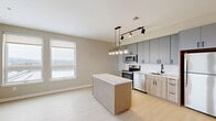 Located at 630 Kenilworth Terrace NE in Washington, DC, this thoughtfully designed two-bedroom, two-bathroom residence offers a clean, modern aesthetic throughout its single-floor layout. Light-toned hardwood flooring runs continuously across the living areas and bedrooms, complementing the neutral warm-gray wall palette and bright white trim for a cohesive, contemporary feel.

The open-concept kitchen is a standout feature, anchored by a central island with a white quartz countertop and natural wood base. Two-tone cabinetry pairs slate-gray upper cabinets with light wood lower cabinets, accented by matte black hardware. A white subway tile backsplash, stainless steel appliances — including a range, microwave, dishwasher, and refrigerator — and a stylish multi-pendant chandelier with track lighting complete the space. A large window floods the kitchen and living area with natural light and offers open exterior views.

Both bedrooms are well-proportioned and filled with natural light. The primary bedroom features dual windows overlooking the surrounding neighborhood, while the second bedroom includes a double-door closet. Each bathroom is finished with large-format tile, a soaking tub with shower, wood-toned vanity, matte black fixtures, and a framed mirror — delivering a clean, spa-inspired feel throughout.