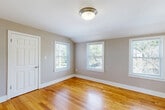 Located at 62 Macarthur Circle East in South Portland, Maine, this three-bedroom, one-bathroom home offers a practical and comfortable single-floor layout. Warm hardwood flooring flows throughout the majority of the home, lending a consistent and inviting character to the living spaces.

The kitchen is well-equipped with honey-toned wood cabinetry, granite-style countertops, and a full suite of stainless steel appliances including a gas range, microwave, dishwasher, and refrigerator. Tile flooring completes the functional design of this space.

Each of the three bedrooms features neutral taupe walls, hardwood floors, and ample natural light from multiple windows offering views of the surrounding greenery. Two of the bedrooms include sliding-door closets for convenient storage, while a third bedroom features open shelving and tile flooring with a vaulted ceiling detail, adding architectural interest.

The bathroom is clean and efficiently designed, featuring a full tub-shower combination, a white vanity with storage, and tile flooring. A central hallway connects the rooms and provides easy navigation throughout the home. The overall aesthetic is bright, neutral, and move-in ready, making this South Portland home a straightforward and functional living space.