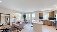 This single-floor residence showcases a thoughtfully designed open-concept layout that seamlessly connects the living, dining, and kitchen areas. The living space is bathed in natural light, courtesy of expansive floor-to-ceiling windows that frame outdoor views of surrounding greenery. Light hardwood-style flooring runs throughout, complementing the clean, neutral palette of the interior.

The kitchen is a standout feature, equipped with warm wood-tone cabinetry, a dark tile backsplash, stainless steel appliances — including a gas range, built-in microwave, and French door refrigerator — and a generous white quartz island that doubles as a casual dining surface. A window above the sink brings in additional natural light.

The living and dining areas offer an airy, open feel with recessed lighting and multiple windows providing bright, cheerful ambiance and outdoor views.

Two well-proportioned bedrooms offer comfortable retreats, each with soft carpeting, ample natural light, and neutral tones. The bathrooms are finished with modern fixtures: one features a large walk-in glass shower with full-tile surround and built-in shelving, while the second includes a sleek wood vanity with a white quartz countertop and a large mirror. The overall design is clean, contemporary, and move-in ready.