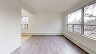 Located at 46 Saranac Blvd, Suite 301, in Toronto's Lawrence Heights neighbourhood, this one-bedroom, one-bathroom unit offers a clean, functional layout across a single floor. The space is finished in a bright, neutral palette throughout, creating a light and airy ambiance.

The open-plan living area is a standout feature, with multiple large windows on two walls that invite generous natural light and offer views of the surrounding tree-lined streetscape. Light grey laminate wood flooring runs throughout the living and bedroom areas, while baseboard heating runs along the perimeter walls.

The galley-style kitchen is efficiently laid out with white cabinetry extending to ceiling height, white tile backsplash, light tile flooring, and white appliances including an electric coil stove and full-sized refrigerator. A window above the sink further brightens the space.

The bedroom is a comfortable size, featuring the same light wood flooring, a double-door closet, and a window with an outdoor view. The bathroom includes a full soaker tub with floor-to-ceiling beige tile surround, offering a clean and classic finish.

A hallway connects all rooms, providing a logical and practical flow throughout this well-maintained unit.