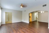 Located in Atlanta, GA (30327), this single-floor residence offers a thoughtfully designed layout with a cohesive, neutral color palette and a variety of quality finishes across its living spaces. The main living area makes a strong impression with rich, dark hardwood flooring and two sets of double French-style windows fitted with white blinds, allowing natural light to fill the room. A ceiling fan adds both function and character overhead. An elegant arched passageway connects the living area to an adjacent dining space, which is accented by a classic chandelier, creating a seamless and inviting flow. The kitchen is well-appointed with white shaker-style cabinetry, granite countertops, a subway tile backsplash, and a full suite of stainless steel appliances including a range, microwave, and refrigerator. Light ceramic tile flooring completes the clean, practical look. The bedrooms feature plush carpeting, neutral taupe walls, and windows with views of surrounding greenery, offering a calm and comfortable retreat. Each room is served by ceiling fans and generous wall space. The bathroom is finished with white tile flooring, a granite-topped vanity with white cabinetry and brushed nickel hardware, and a full tub-shower combination, providing a functional and well-maintained space.