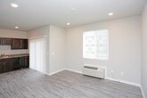 This single-floor residence offers a thoughtfully designed layout with a cohesive blend of comfort and practicality. The kitchen serves as a functional centerpiece, featuring rich dark espresso cabinetry with brushed nickel hardware, granite-style countertops, and a full suite of black appliances including a refrigerator, range, built-in microwave, and dishwasher. Light wood-look flooring runs throughout the kitchen and living areas, lending a clean, modern aesthetic throughout.

The open living area connects seamlessly to the kitchen via a sliding barn-style door, and benefits from recessed lighting, neutral warm-toned walls, and a sliding glass door that opens to an outdoor balcony, allowing natural light to fill the space. A wall-mounted PTAC unit provides convenient climate control.

The bedroom is finished with plush carpeting underfoot and a ceiling fan with integrated lighting, creating a comfortable and restful atmosphere. Ample closet space with bifold doors adds practical storage.

The bathroom is clean and functional, offering a full soaking tub with an overhead shower, a brushed nickel fixture set, and a vanity with a granite-style countertop and dark wood cabinetry. Neutral gray walls and wood-look flooring complete the refined, understated aesthetic throughout this well-designed space.