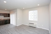 This single-floor residence offers a thoughtfully designed layout with a cohesive blend of comfort and practicality. The kitchen serves as a functional centerpiece, featuring rich dark espresso cabinetry with brushed nickel hardware, granite-style countertops, and a full suite of black appliances including a refrigerator, range, built-in microwave, and dishwasher. Light wood-look flooring runs throughout the kitchen and living areas, lending a clean, modern aesthetic throughout.

The open living area connects seamlessly to the kitchen via a sliding barn-style door, and benefits from recessed lighting, neutral warm-toned walls, and a sliding glass door that opens to an outdoor balcony, allowing natural light to fill the space. A wall-mounted PTAC unit provides convenient climate control.

The bedroom is finished with plush carpeting underfoot and a ceiling fan with integrated lighting, creating a comfortable and restful atmosphere. Ample closet space with bifold doors adds practical storage.

The bathroom is clean and functional, offering a full soaking tub with an overhead shower, a brushed nickel fixture set, and a vanity with a granite-style countertop and dark wood cabinetry. Neutral gray walls and wood-look flooring complete the refined, understated aesthetic throughout this well-designed space.
