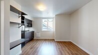 Located in the Phinney Ridge neighborhood of Seattle, Unit 35 at 3635 Phinney Ave N offers a thoughtfully designed single-floor studio layout that maximizes every inch of its space. Warm wood-look flooring runs continuously throughout, lending a cohesive and inviting feel to the entire unit.

The kitchenette is outfitted with sleek dark-toned cabinetry, stainless steel countertops, a single-basin sink, an overhead microwave, and a full-size refrigerator alongside open shelving for added storage. The clean, modern aesthetic carries into the main living area, which is bathed in natural light from a window with views of the surrounding neighborhood rooftops.

A built-in organizational station near the entry features open wall shelves, a hanging rod, and a fold-down desk surface — ideal for remote work or daily use. The electrical panel is neatly integrated into this entryway wall. The bathroom includes a walk-in shower stall finished in clean white tile with a built-in niche and chrome fixtures, maintaining the unit's minimalist design language.

The bright, neutral wall palette and efficient use of built-in features make this studio a functional and modern living space in one of Seattle's well-connected residential neighborhoods.