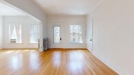 Located on East South Temple Street in Salt Lake City, this 2-bedroom, 1-bathroom unit blends classic architectural character with practical living spaces. Warm hardwood floors flow throughout the main living areas and bedrooms, complemented by crisp white walls and clean crown molding that lend a bright, airy feel to the interior.

The living room is a welcoming space defined by a graceful arched passageway that connects seamlessly to the rest of the unit. Natural light filters in through multiple windows, including a glazed entry door, creating a pleasant and open atmosphere. A traditional cast-iron radiator adds a period-appropriate touch.

The kitchen features white tile flooring, gray lower cabinetry with white upper cabinets, a gas range, and a full-size refrigerator. Built-in shelving and ample storage make it both functional and organized. The kitchen opens toward a carpeted secondary bedroom, which offers built-in upper cabinetry and good natural light.

The primary bedroom features hardwood floors, crown molding, a frosted-glass panel door, and access to a dedicated closet. The bathroom retains its classic charm with a black-and-white hexagonal mosaic tile floor, white subway-tiled walls, a pedestal sink, and a bathtub with shower — a thoughtfully preserved vintage aesthetic throughout.