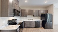 Located at 1202 N Main St in Nixa, Missouri, this single-floor unit offers a thoughtfully designed layout with contemporary finishes throughout. The kitchen serves as a central highlight, featuring rich dark-toned shaker-style cabinetry that extends to the ceiling for generous storage capacity. Marble-look countertops provide a clean, elegant work surface, complemented by a full suite of black appliances including a range, microwave, dishwasher, and refrigerator. Light wood-look hard flooring runs through the kitchen and living areas, creating a warm, cohesive aesthetic.

The open layout connects the kitchen directly to the living area, which benefits from a sliding glass door that brings in ample natural light. The bedrooms are carpeted for comfort and each feature windows with blinds that allow for outdoor views and natural light. A walk-in closet with wire shelving provides practical storage in the bedroom area.

The bathroom continues the unit's consistent design language, with a marble-look vanity countertop, dark cabinetry, brushed nickel hardware, and a grab bar, reflecting both style and functionality throughout this well-finished space.