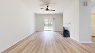 This well-appointed one-bedroom, one-bathroom residence at 300 Gatehouse Ln in Odenton, Maryland offers a clean, modern aesthetic throughout its single-floor layout. The open living room serves as the heart of the home, featuring light hardwood-style flooring, a classic fireplace with a sleek black surround and built-in shelving, and a ceiling fan overhead. A sliding glass door floods the space with natural light while providing direct views of the surrounding greenery outside.

The kitchen is thoughtfully designed with white shaker-style cabinetry, striking black hardware, quartz countertops with a subtle veining pattern, and a full suite of stainless steel appliances including a range, over-the-range microwave, and dishwasher. A matte black faucet complements the undermount sink, adding a contemporary touch.

The bedroom offers a comfortable, carpeted retreat with a sizable closet, a window with horizontal blinds that invites natural light, and a ceiling fan for year-round comfort. A second carpeted area leads to the hallway and main living spaces.

The bathroom is clean and modern, featuring a white vanity with shaker-style cabinet doors, a wood-framed mirror, matte black fixtures, and a full tub-shower combination, all set above light wood-look flooring. Together, these spaces create a cohesive and inviting home.
