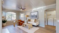 Located at 5151 E Guadalupe Rd in Phoenix, AZ, this well-appointed single-story, one-bedroom, one-bathroom home offers a thoughtfully designed layout across a comfortable footprint. The living room serves as the heart of the space, featuring crown molding, light wood-style flooring, a ceiling fan, and a white-framed fireplace flanked by arched windows that fill the room with natural light. An adjacent dining area continues the bright aesthetic with large arched windows overlooking lush outdoor greenery, complemented by an elegant pendant light fixture. The kitchen is outfitted with white cabinetry, quartz-style countertops, stainless steel appliances including a refrigerator, range, microwave, and dishwasher, plus a window above the sink for added brightness. The primary bedroom offers a serene retreat with a ceiling fan, wood-style flooring, a desert-themed wall painting, and direct access to a private balcony showcasing scenic palm tree views. A spacious walk-in closet with built-in shelving and hanging rods provides generous storage. The bathroom includes a full tub-shower combination, a wide vanity with quartz countertops, and a large mirror. A dedicated office and hallway complete the functional floor plan of this inviting Phoenix home.