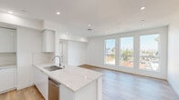 Located at 4808 Oakwood in the heart of Los Angeles, this two-bedroom, one-bathroom unit offers a contemporary design with a clean, minimalist aesthetic. The open-concept layout connects the kitchen and living area seamlessly, creating an efficient and functional living space. Light wood-tone flooring runs throughout, complementing the crisp white walls and recessed lighting overhead.

The kitchen is a standout feature, equipped with high-gloss white cabinetry extending to the ceiling, a large quartz waterfall-edge island with an undermount sink, and a full suite of stainless steel appliances including a gas range, built-in microwave, refrigerator, and dishwasher. A tile backsplash adds a refined finishing detail.

The living area benefits from large windows that frame views of the surrounding Los Angeles neighborhood, including palm trees and city skyline elements. Both bedrooms continue the light, airy aesthetic with wood flooring, white walls, and windows that bring in natural daylight and outdoor views. Each bedroom includes a built-in double-door closet for storage.

The bathroom features large-format tile flooring, a soaking tub with tiled surround, a marble-topped vanity with an illuminated mirror, and clean, neutral finishes throughout.