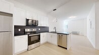 Located at 540 Bond Street in Bridgeport, CT, this thoughtfully designed 2-bedroom, 2-bathroom unit offers a clean, modern aesthetic across a well-utilized single floor. Light-toned hardwood flooring runs throughout, complementing the bright white walls and creating a cohesive, airy feel.

The open-concept kitchen and living area serves as the heart of the unit. The kitchen features white cabinetry with gold hardware, dark granite countertops, a dark tile backsplash, and a full suite of stainless steel appliances including a refrigerator, electric range, microwave, and dishwasher. A contemporary circular pendant light anchors the space above the kitchen peninsula.

The entry hallway is flanked by closets with black hardware, providing generous storage. Both bedrooms offer light-filled, quiet retreats with hardwood floors and wall-unit PTAC heating and cooling. The spacious primary bedroom includes its own access to a bathroom, while the second bedroom is well-proportioned and versatile.

Each of the two bathrooms features terrazzo-style tile flooring, a tub-shower combination with crisp white surround, and matte black fixtures and hardware, adding a refined contrast to the otherwise bright, minimalist design. With four closets total, storage is abundant throughout this clean, move-in-ready unit.