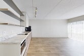 This single-floor unit in Chattanooga, Tennessee offers a clean, modern aesthetic throughout, characterized by light wood-tone flooring that extends seamlessly across every room, creating a cohesive and airy feel. The open layout maximizes the available space, allowing natural light to flow through large sliding glass doors fitted with vertical blinds in the main living area. These doors provide outdoor views and bathe the space in abundant daylight, enhancing the bright, neutral color palette of white and warm beige tones on the walls and ceilings.

The kitchen is a functional highlight, featuring a sleek marble-style countertop, light wood cabinetry with open shelving above, a stainless steel refrigerator, a built-in cooktop, and a microwave. Track lighting runs along the ceiling, providing well-distributed illumination across the cooking and prep areas. Open shelving adds both practicality and a contemporary design element.

The bathroom is efficiently designed with wood-look tile flooring, a floating vanity with an integrated sink, a large wall mirror, and a towel bar. Conveniently situated adjacent to the bathroom is an in-unit washer, adding practical functionality to the layout. A wall-mounted HVAC unit services the living area, ensuring climate control throughout. Overall, the space presents a minimalist, well-maintained environment well-suited for modern urban living.
