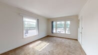 Located at 3053 Stocker Pl in the Leimert Park neighborhood of Los Angeles, this single-floor unit offers a straightforward and functional layout filled with natural light. The living area is generously sized, featuring neutral-toned wall-to-wall carpeting and multiple large windows that allow ample sunlight to stream in, providing views of the surrounding neighborhood. Built-in shelving adds a practical touch to the living space, while a wall-mounted heater and a front entry door with hardware complete the room. An adjacent area showcases warm hardwood flooring, white cabinetry with a built-in countertop and sink, and a window with vertical blinds — ideal for use as a utility or flex space. The bedroom is bright and comfortable, also carpeted, with a large window overlooking the exterior and direct access to the adjoining rooms. The bathroom features a distinctive deep-red diamond-pattern tile floor, a white vanity with mirror, a toilet, and a bathtub, all accented by crisp white walls and a frosted window for privacy. Throughout the unit, a clean, neutral color palette of white walls and light trim creates a cohesive and move-in ready atmosphere well-suited to the Southern California lifestyle.