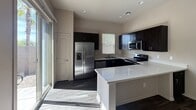 This 800-square-foot, single-story residence at 150 E Warner Rd, Unit 146, Gilbert, AZ offers 2 bedrooms and 1 bathroom with a clean, modern aesthetic throughout. Dark hardwood-style flooring runs consistently across all rooms, creating a cohesive and contemporary feel.

The kitchen is a standout feature, equipped with stainless steel appliances including a French door refrigerator, electric range, built-in microwave, and dishwasher. Dark espresso cabinetry contrasts sharply with bright white quartz countertops, which extend to a peninsula-style breakfast bar. A window above the sink provides natural light, while recessed lighting adds additional illumination.

Both bedrooms feature dark hardwood-style flooring, ceiling fans, and windows with blinds allowing ample natural light. The spacious primary bedroom measures 240 square feet and includes access to a dedicated closet. The second bedroom is similarly appointed with windows on two walls.

The bathroom is finished with matching dark cabinetry, a white countertop vanity, a shower with a glass door, and a narrow window for ventilation and natural light. Dark flooring continues here, maintaining the unit's consistent design language.

Overall, the unit presents a modern, neutral palette with dark floors, soft gray walls, and clean white trim throughout.