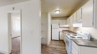 Located at 2033 Jerry Murphy Rd in Pueblo, Colorado, this single-floor unit offers a practical and well-organized layout throughout. The galley-style kitchen is efficiently designed with white cabinetry extending to the ceiling, granite-look laminate countertops, a stainless steel sink, and white appliances including an electric range, refrigerator, and dishwasher. Wood-look vinyl plank flooring runs through the kitchen and extends into the adjacent living area, adding a cohesive and easy-to-maintain finish. A dedicated pantry or storage closet is accessible directly from the kitchen, providing additional organizational space. The open living area is bright and airy, featuring a large window dressed with vertical blinds that allows natural light to fill the room, along with a ceiling fan and a baseboard heating unit. The bedrooms are carpeted for comfort and include windows with views of surrounding greenery, as well as baseboard heating. The bathroom is outfitted with a full-size tub and shower combination, accented by clean white tile surround. Textured ceilings are present throughout the unit, consistent with the overall utilitarian yet functional character of this Pueblo-area residence.